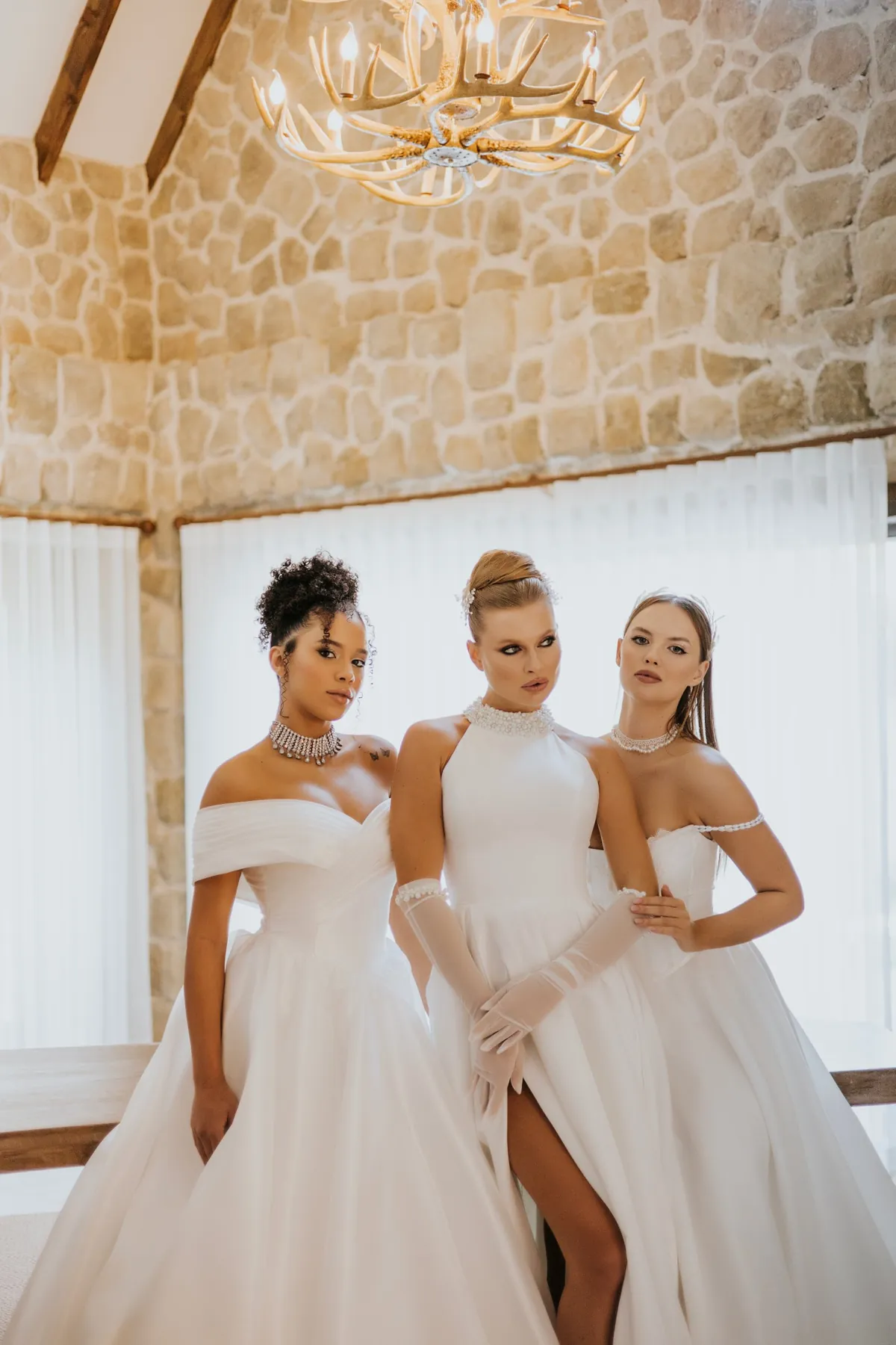 Henna Bride gelinlik koleksiyonundan üç model, taş duvarlı salonda