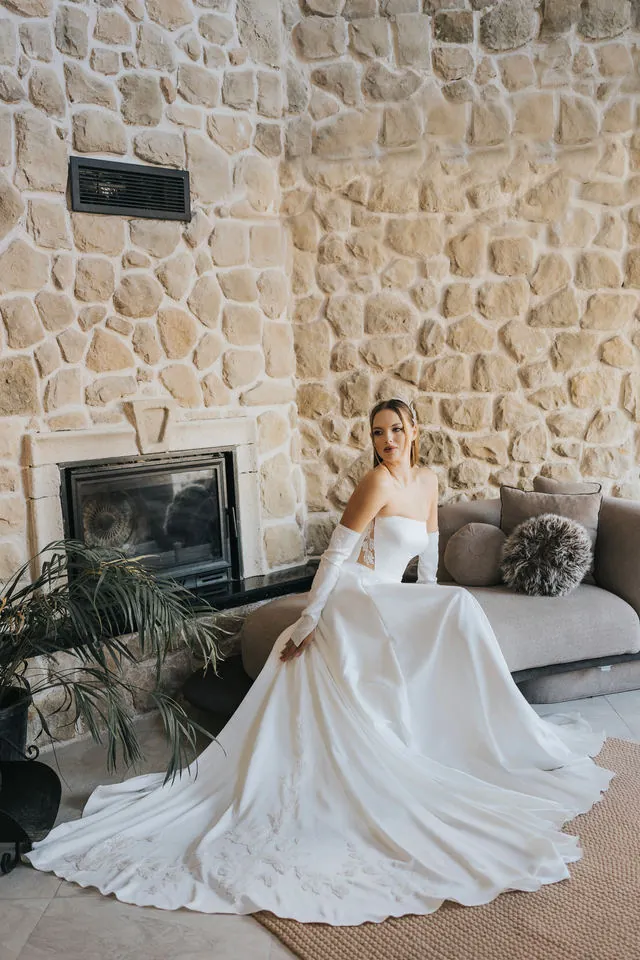 Gown with a long train beside a stone fireplace